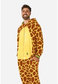 Tutina con motivo di giraffa in morbido pile giallo, con macchie marroni, zip frontale e un piccolo logo di palma sulla tasca.