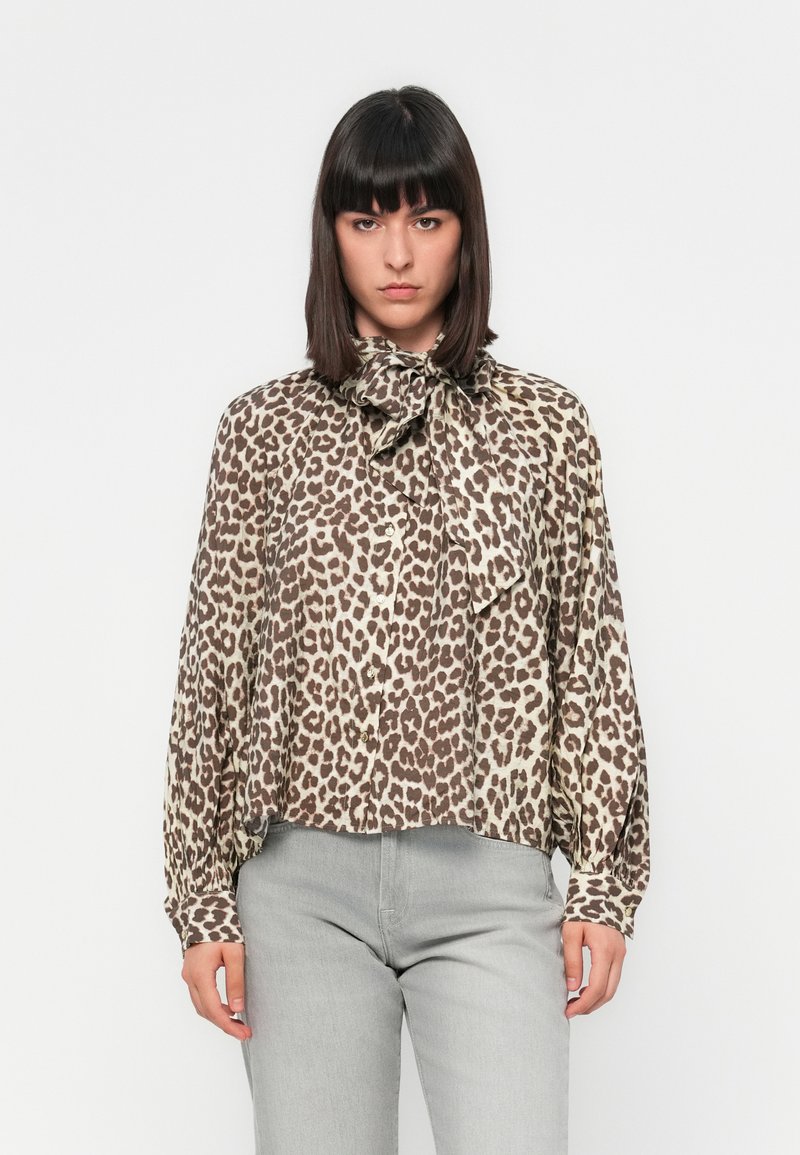 Blusa a stampa leopardata in tessuto leggero, con colletto a fiocco, chiusura frontale con bottoni e maniche lunghe. Palette di colori neutri con accenti marroni.