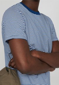 Blau-weiß gestreiftes T-Shirt mit rundem Halsausschnitt, kurzen Ärmeln und lockerer Passform. Die Textur wirkt glatt; es zeigt sichtbare horizontale Linien.