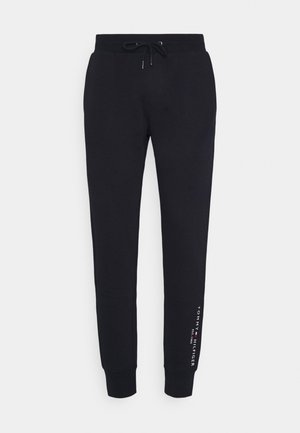 Schwarze, schmal geschnittene Jogginghosen mit Kordelzugbund und vertikal gedrucktem Tommy Hilfiger-Logo nahe dem linken Knöchel.