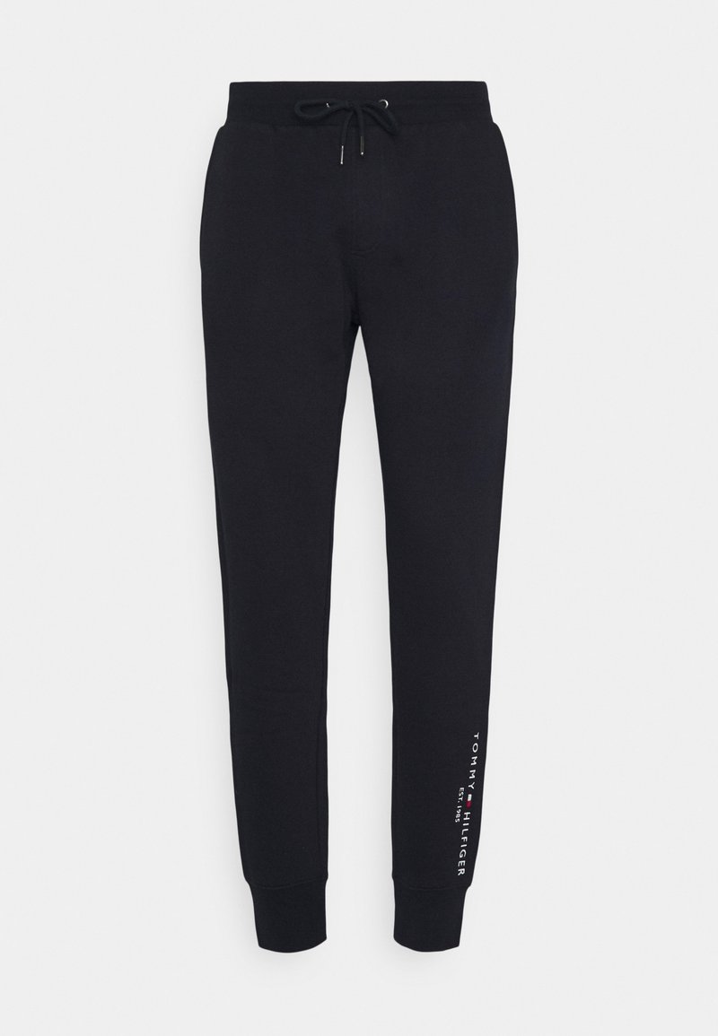 Svarta tapered joggare med dragsko vid midjan och Tommy Hilfiger-logotypen tryckt vertikalt nära vänster vrist.