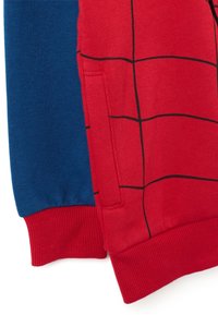 Los sudaderas rojas y azules presentan un patrón de cuadros en la pieza roja, con puños acanalados y un bolsillo lateral en la tela roja.