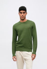 Πράσινο πλεκτό πουλόβερ με υφασμάτινο ριγέ μοτίβο, στρογγυλή λαιμόκοψη και ribbed μανίκια και στρίφωμα, με ένα μικρό λογότυπο στο στήθος.