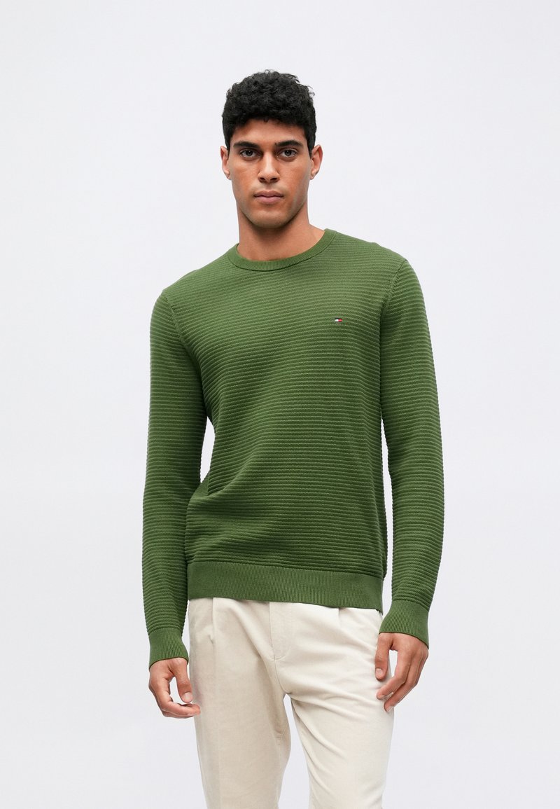 Πράσινο πλεκτό πουλόβερ με υφασμάτινο ριγέ μοτίβο, στρογγυλή λαιμόκοψη και ribbed μανίκια και στρίφωμα, με ένα μικρό λογότυπο στο στήθος.