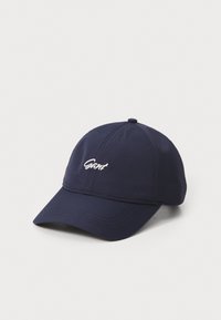 Navy blue baseball cap made of fabric, featuring a stitched seam design and an embroidered logo on the front. Curved visor shape.
