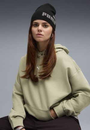 Light green hoodie with kangaroo pocket, featuring a white logo; paired with a black beanie showing gray text. Smooth texture, relaxed fit.