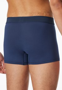 Marinblå boxershorts i elastiskt material, med en mjuk elastisk midjeresår och platta sömmar för komfort. Skurna till midjan längd.