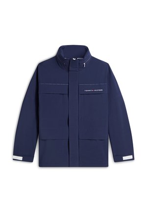 Veste bleue marine zippée avec col montant, deux grandes poches avant et logo Tommy Hilfiger sur la poitrine, avec des détails réfléchissants aux poignets.