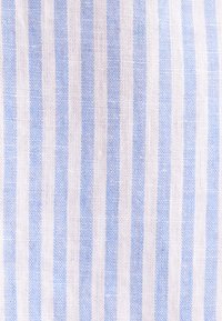 Gros plan d'un tissu tissé avec des rayures verticales bleu clair et blanches dans un motif régulier.