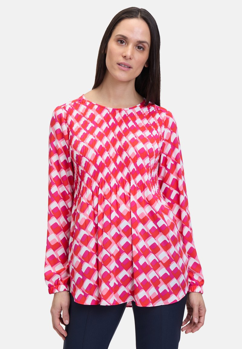 Blusa a maniche lunghe in un vivace motivo geometrico rosa e bianco, realizzata in un tessuto leggero con dettagli plissettati sul collo.