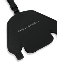 Black leather luggage tag with a distinct shape and smooth texture, featuring silver embossed "KARL LAGERFELD" branding on the front.