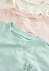 Trii crew-neck dukserice složene: mentol zelena, nježno ružičasta i svijetla bež. Svaka ima rebraste ovratnike i malu izvezenu riječ "ljubav".