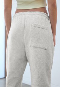 Ljusgrå mjukisbyxor av mjukt tyg, med elastisk midja och en bakficka.