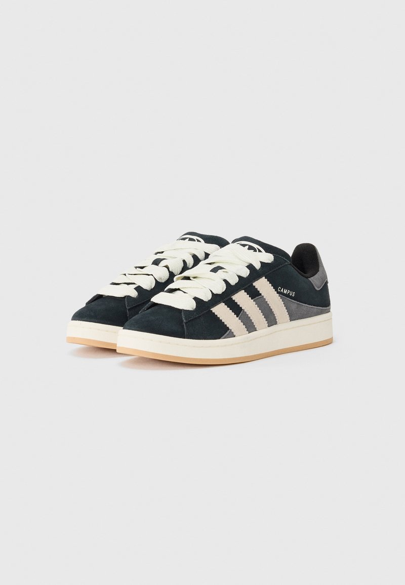 Zapatillas de ante verde oscuro con tres franjas claras, cordones crema y suela marrón claro, etiquetadas como "CAMPUS" en el lateral.