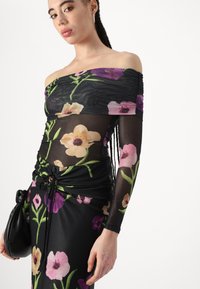 Abito floreale off-the-shoulder realizzato in un tessuto nero trasparente con motivi di fiori viola e rosa, design arricciato e dettagli con cordoncino.