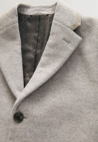 Grå uldblandingsfrakke med slidskrave, enkelt knaplukning og en glat mønstret foring. Har en subtil tekstur og skræddersyet pasform.