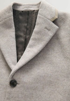 Palton gri dintr-un amestec de lână, cu guler cu vârf, închidere cu un singur nasture și o căptușeală netedă cu model. Prezintă o textură subtilă și o croială ajustată.