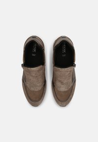 Brown suede slip-on shoes with textured uppers, a contrasting strip along the sides, and a rubber sole. Features elastic side panels for easy wear.