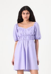 Robe lavande à manches bouffantes avec encolure carrée, buste froncé et élastique à la taille pour un ajustement décontracté, fabriquée en tissu léger.