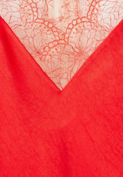 Tessuto di raso rosso con scollatura a V sovrapposta da un pizzo beige trasparente con motivi floreali.