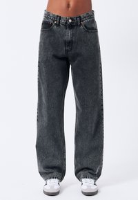 Jeans in denim neri a gamba ampia con lavaggio sbiadito. Tra le caratteristiche ci sono la chiusura con bottone, cinque tasche e dettagli di cucitura a contrasto.