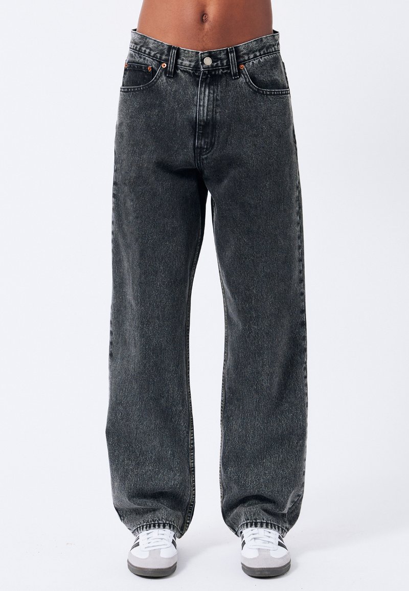 Jeans in denim neri a gamba ampia con lavaggio sbiadito. Tra le caratteristiche ci sono la chiusura con bottone, cinque tasche e dettagli di cucitura a contrasto.