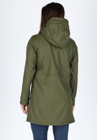 Giacca impermeabile verde oliva con cappuccio, texture liscia, maniche lunghe e orlo curvo. Presenta una silhouette aderente e dettagli delle cuciture.