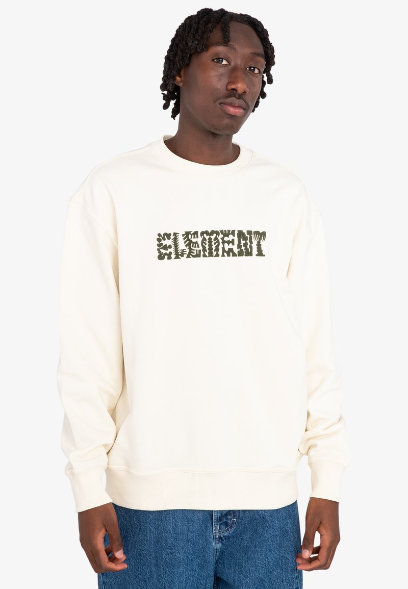 Cream sweatshirt with a textured green "ELEMENT" logo. Features ribbed cuffs and hem, relaxed fit, and soft cotton material. Blue denim jeans worn.