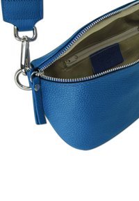 Blauwe leren schoudertas met een gestructureerd oppervlak, zilveren rits en een binnenvak. Voorzien van een afneembare schouderriem en een ronde vorm.