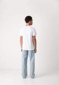 White short-sleeve t-shirt with a round neck, paired with light blue wide-leg jeans. Minimalistic design, smooth fabric texture.