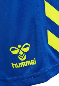 Blauer Stoff mit leuchtend gelbem hummel-Logo, das eine stilisierte Biene und zwei Chevron-Zeichen an der Seite zeigt.