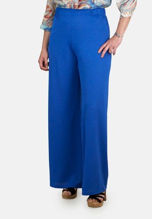 Pantalones de pierna ancha en azul, elaborados con una tela suave y con una cinturilla elástica. Combinados con sandalias de plataforma negras para un contraste.