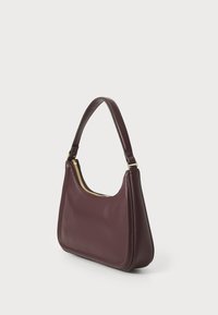 Bordeaux leren handtas met een gebogen vorm, gouden ritsdetails en een enkele strap. Soepele textuur met een minimalistisch ontwerp.