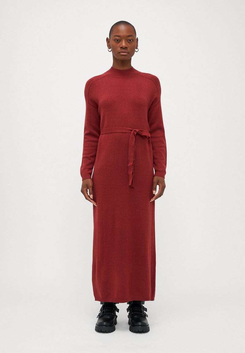 Röd, stickad maxiklänning med långa ärmar, ribbade manschetter och midjeband. Matchad med svarta ankelstövlar med spänne.