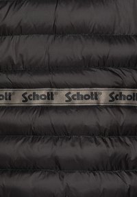 Chaqueta acolchada negra con secciones acolchadas y una banda con el logo de Schott como un acento notable. Textura de tela suave y brillante.