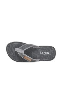 Black flip-flop with fabric straps, featuring a textured footbed and contrasting stitching. A brown accent label reads "KAPORAL JEANS."