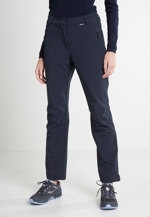 Pantalons d'extérieur bleu marine à coupe slim, avec poches zippées, tissu résistant et texture lisse, associés à des baskets noires.