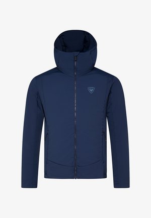 Námorně modrá zateplená bunda s vysokým límcem, plným zipem, bočními kapsami a logem na hrudi. Vyznačuje se hladkou, matnou texturou.