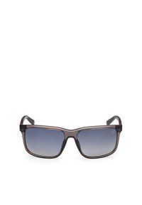 Gafas de sol con un marco de plástico transparente gris oscuro, lentes rectangulares que hacen la transición de un degradado oscuro a uno claro, y gomas texturizadas en las patillas.