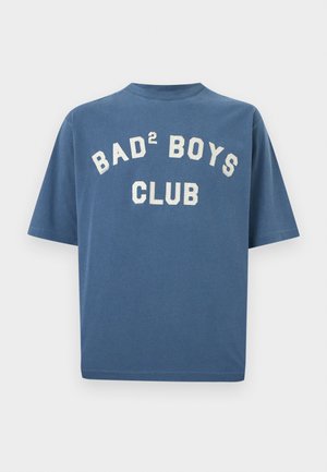T-shirt bleu à manches courtes avec le texte blanc "BAD² BOYS CLUB" imprimé sur le devant en police majuscule et courbée.