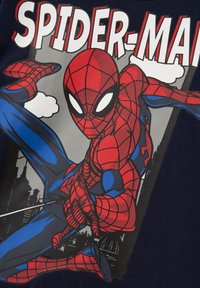 Spider-Man i en rød og blå drakt skyter nett, posert mot en bylandsby med "SPIDER-MAN" tekst over.