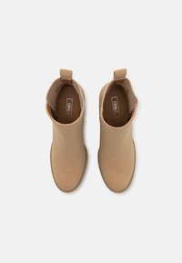 Helle Lederstiefeletten mit glatter Oberfläche, elastischen Seiteneinsätzen und einer kleinen Schlaufe zum Anziehen. Abgerundet mit einer kontrastierenden strukturierten Sohle.