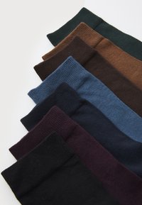 Neuf paires de chaussettes côtelées de différentes couleurs : vert, marron, marine, noir, violet foncé, bleu clair, bleu foncé et marron foncé.