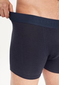 Dunkelmarineblaue Boxershorts aus einem weichen, elastischen Bund mit dem eingeprägten Schriftzug "Reste". Glatte Textur und körperbetonter Schnitt.