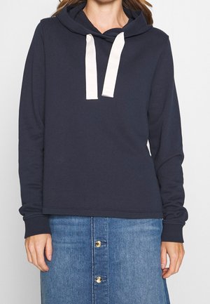Felpa blu navy con tasca a marsupio, dotata di cappuccio con lacci bianchi. Tessuto morbido e testurizzato; vestibilità comoda.