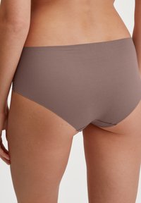 Bruine high-waisted onderbroek gemaakt van zachte, gladde stof. Heeft een eenvoudig ontwerp met een naadloze achterkant en geen zichtbare hardware.