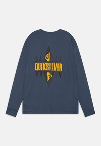Camiseta de manga larga azul marino con un gran diseño geométrico amarillo y negro con el texto "QUIKSILVER" en la espalda. Tela suave, cuello redondo.