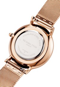 Rose gold stainless steel watch with mesh band, round case, and a reflective back displaying brand and movement details. Water-resistant up to 3ATM.