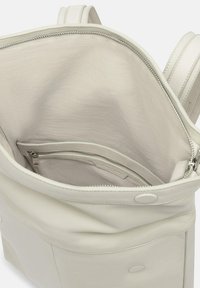 Wnętrze białej skórzanej torby o gładkiej fakturze, z kieszonką na zamek i otwartą przegrodą. Podwójne uchwyty na górze.