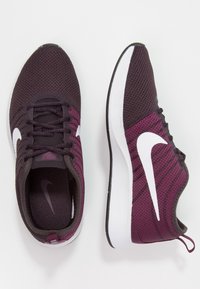 Nike löparskor med en mörklila mesh-överkonstruktion, vit logotyp och texturerade detaljer. Sulan är vit med en robust design.